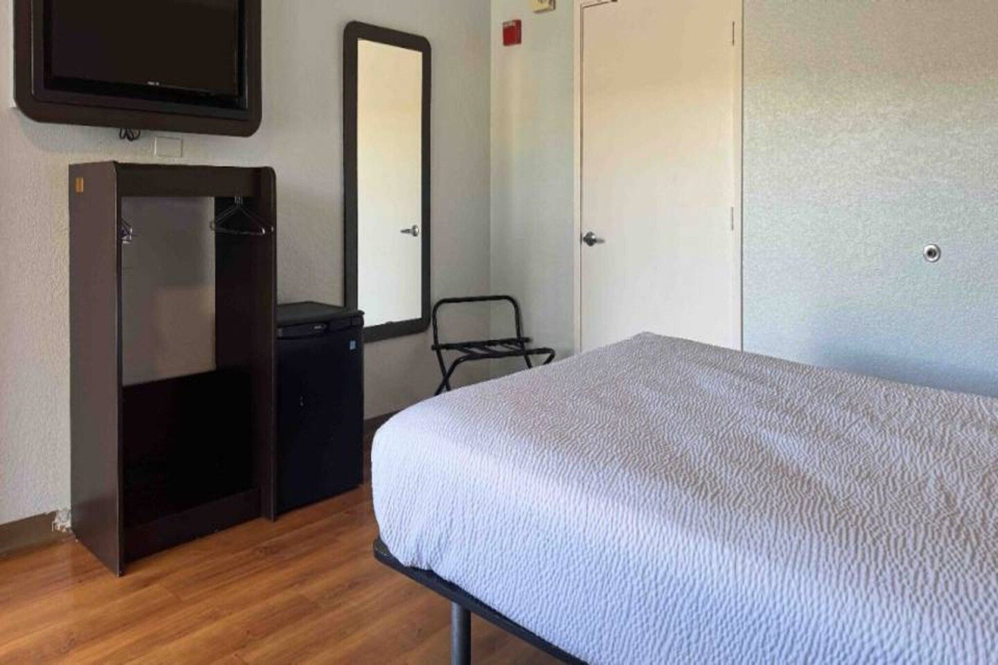 Een slaapkamer met een bed, een kledingkast, een spiegel en een klein bureau.