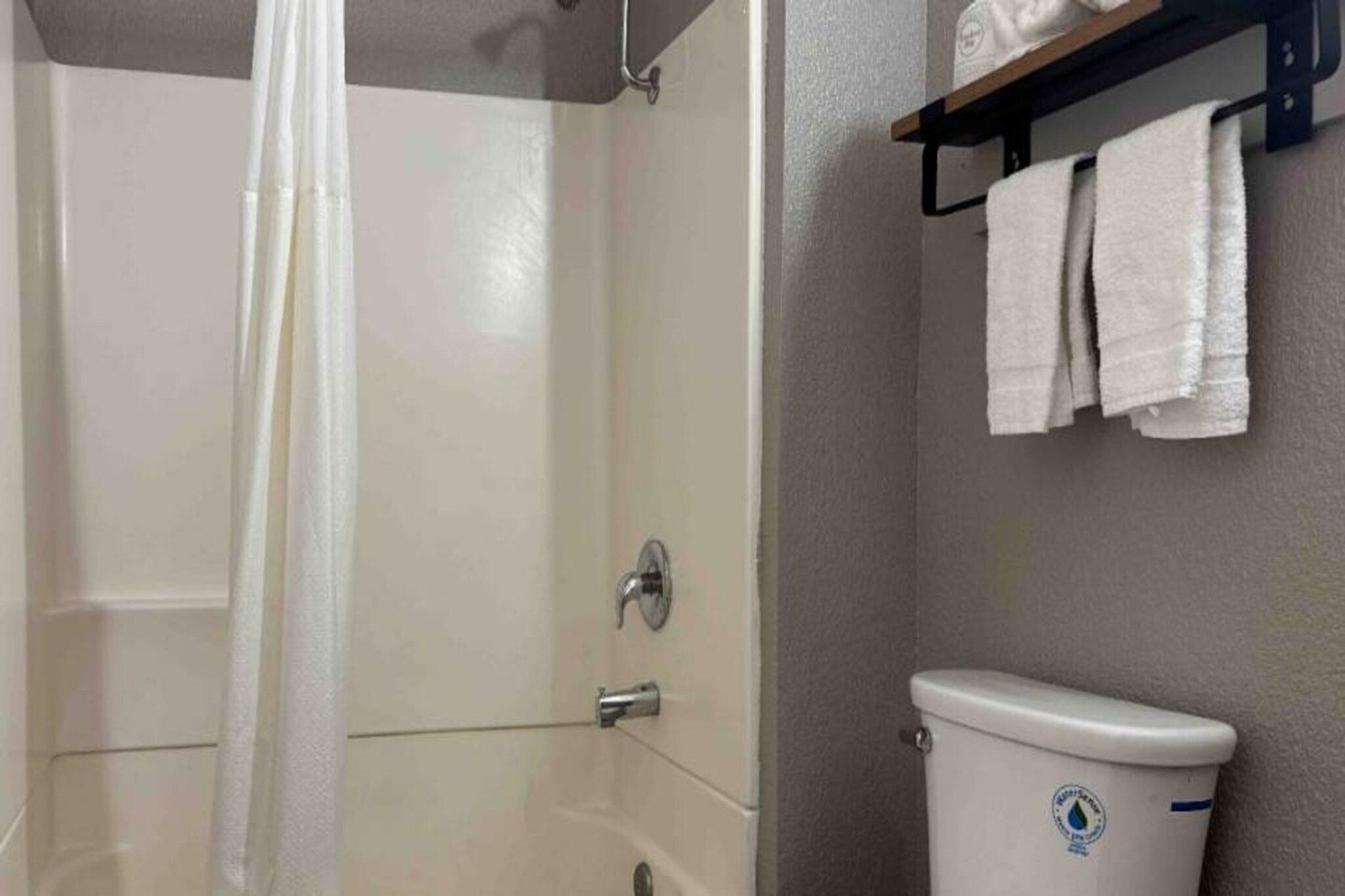 A bathroom with a shower, toilet, and a towel rack.