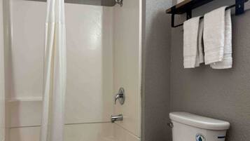 A bathroom with a shower, toilet, and a towel rack.