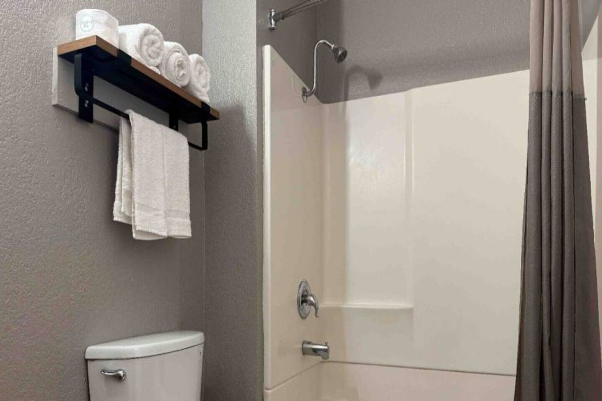 A bathroom with a toilet, a shower stall, and a towel rack with towels.