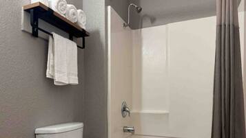 A bathroom with a toilet, a shower stall, and a towel rack with towels.