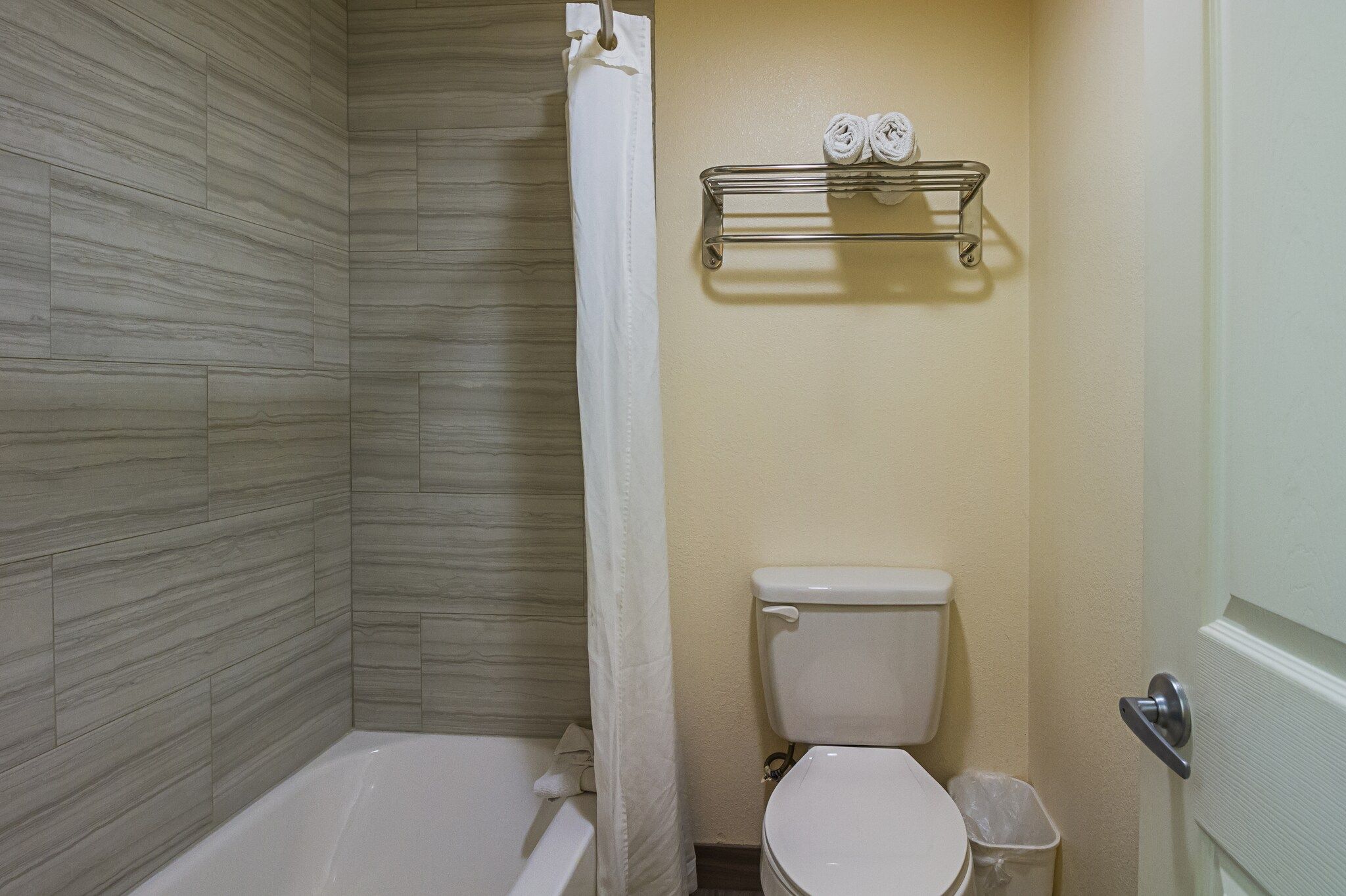 A bathroom with a shower, toilet, and a towel rack.