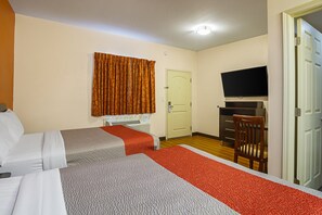 A hotel room with two beds, a television, a desk, and a chair.