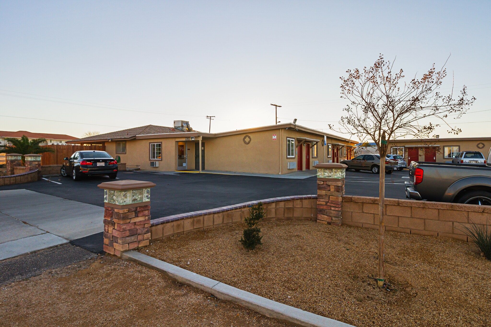 A building with a flat roof, a garage, and a small tree in the foreground.