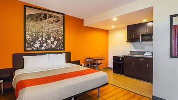 A hotel room with a bed, a desk, and a kitchenette.