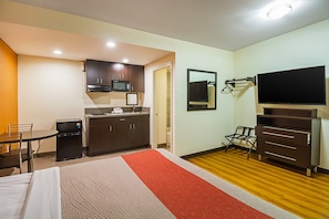 A hotel room with a bed, a desk, a kitchenette, and a TV. - 1 Queen Bed | Non-Smoking, Micfridge (Hesperia)
