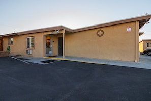 A building with a numbered address sign, a welcome sign, a no parking sign, and a wheelchair-accessible ramp.