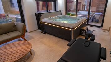 A modern spa room with a hot tub, a massage table, and a wooden table.