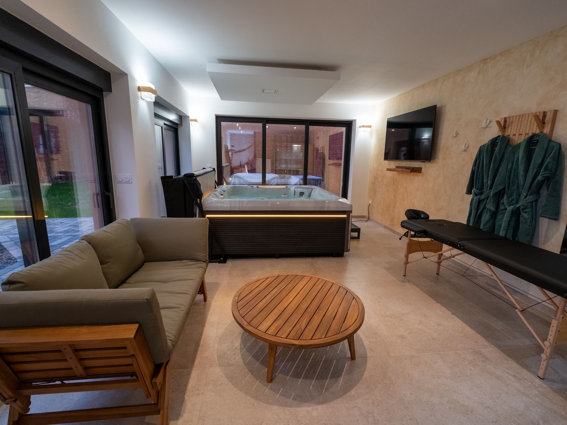 A modern living room with a sofa, a round wooden table, a hot tub, and a bench.
