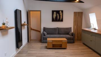 A modern living room with a grey sofa, wooden coffee table, and a painting of feathers on the wall.