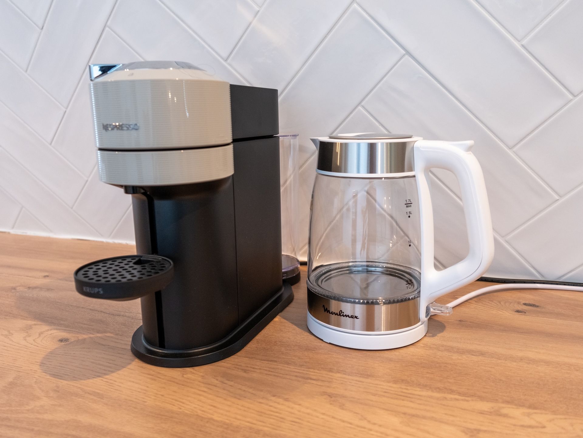 Eine Kaffeemaschine und eine Glaskaraffe auf einer Holztischplatte.