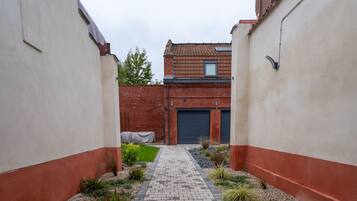 A paved pathway leading to a building with a brick facade and a garage door.