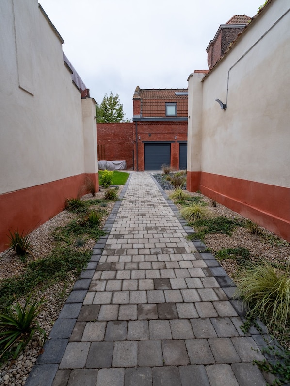 A paved pathway leading to a building with a brick facade and a garage door.