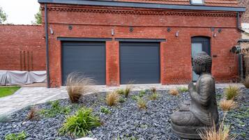 A building with a brick facade, two closed garage doors, and a Buddha statue in the foreground.