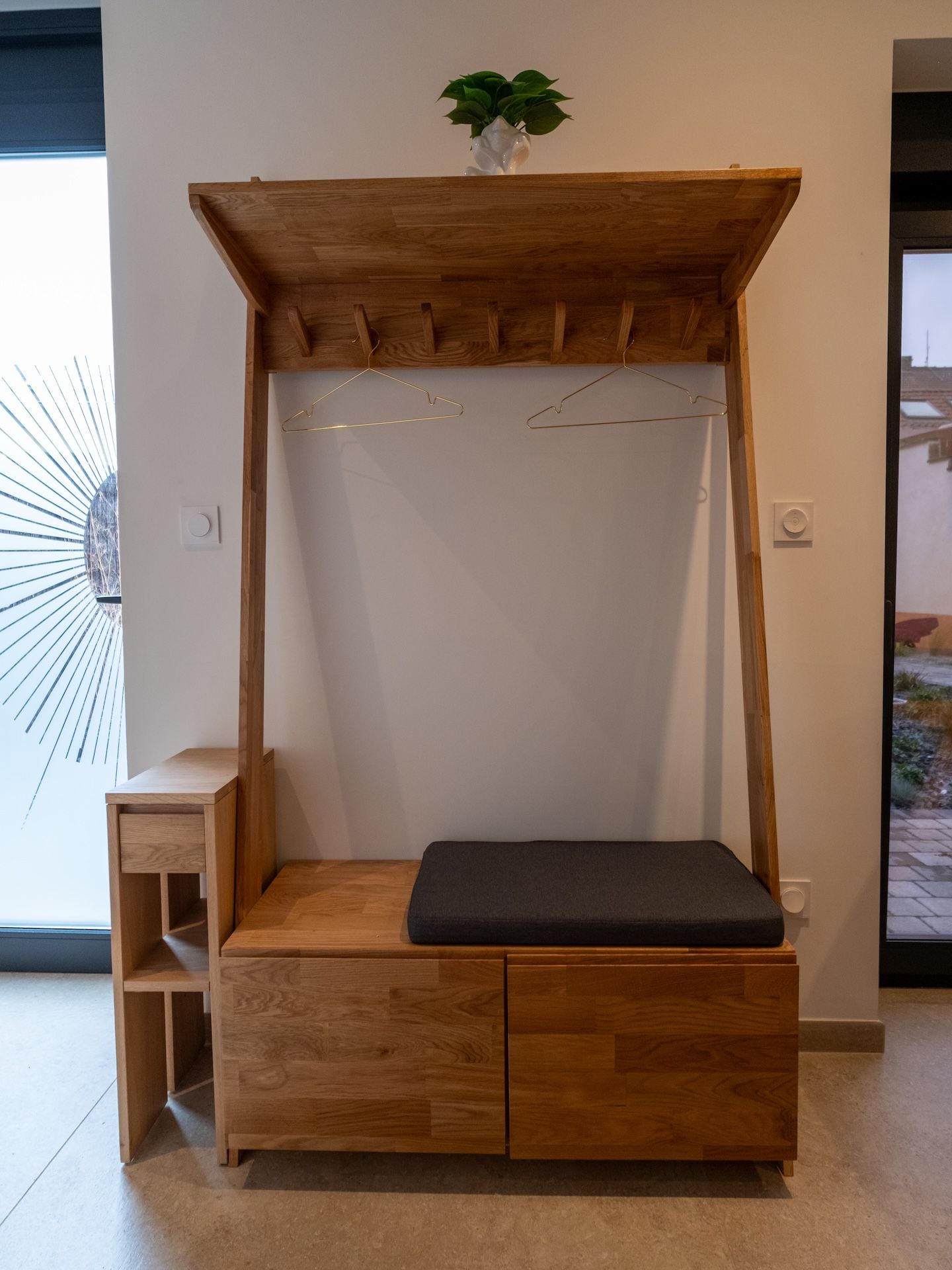 A wooden bench with a backrest and a small plant on top.