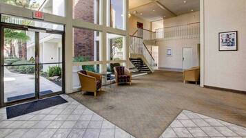 A spacious lobby with a staircase, a reception desk, and a seating area with chairs.