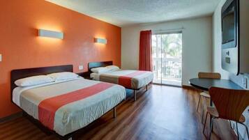 A hotel room with two beds, a dining area, and a large window.