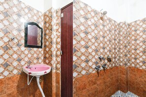 Een badkamer met een roze wastafel, een spiegel en een douchehoek.