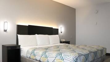 A hotel room with a bed, bedside tables, and wall-mounted light fixtures.