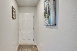A hallway with a white door, a framed picture on the left, and a wall-mounted painting on the right. - 7 Mi to Beach! Group & Pet-Friendly Palm Coast Gem (Palm Coast)