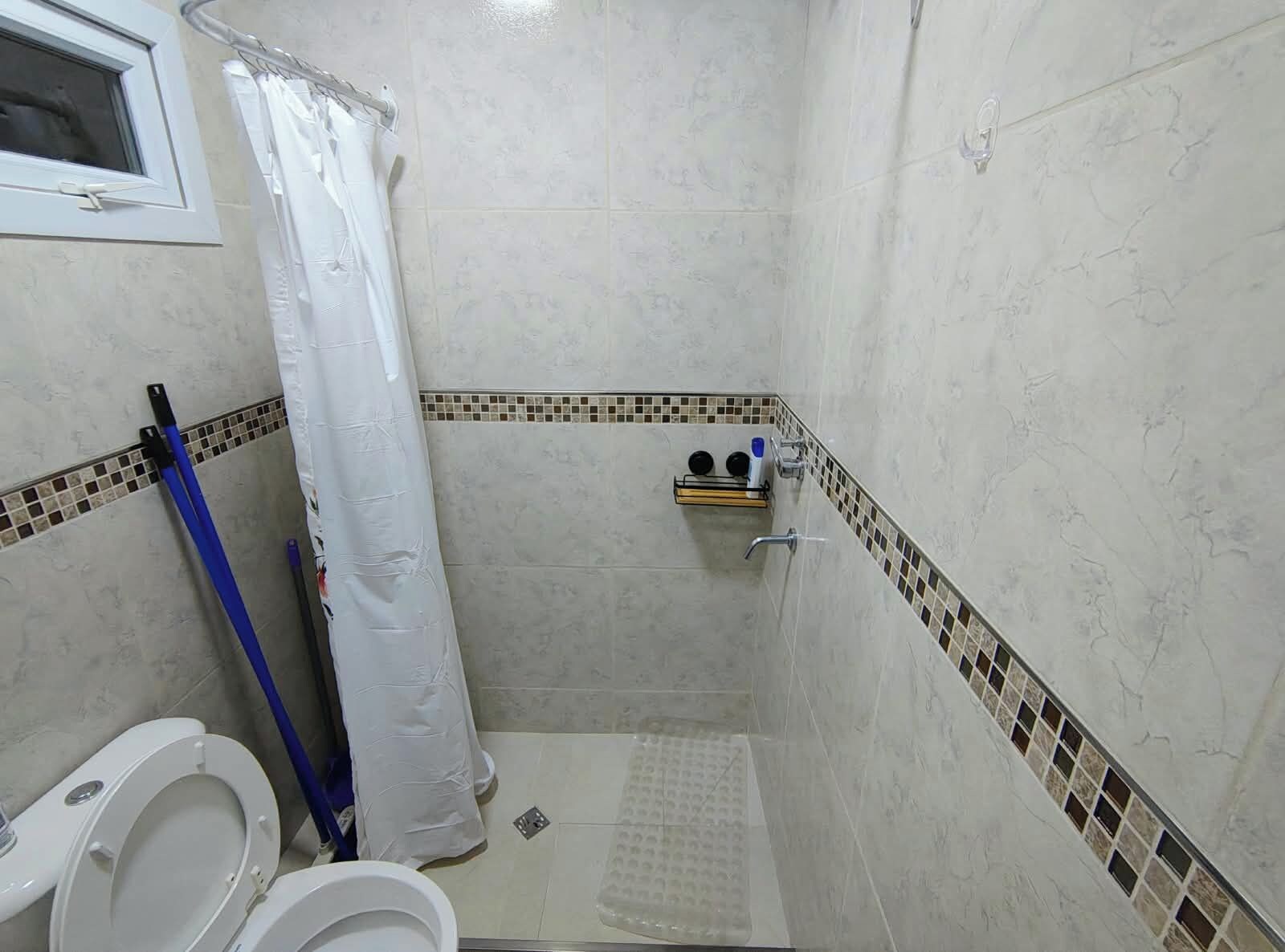 Ein kleines Badezimmer mit Dusche, Toilette und Ablage für Toilettenartikel.