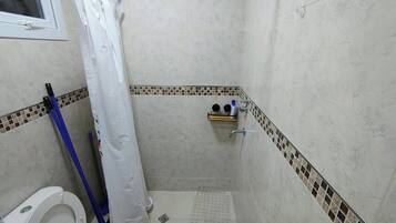 Ein kleines Badezimmer mit Dusche, Toilette und Ablage für Toilettenartikel.