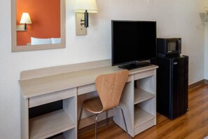 Habitació d'hotel amb escriptori de fusta, televisió, microones i cadira.