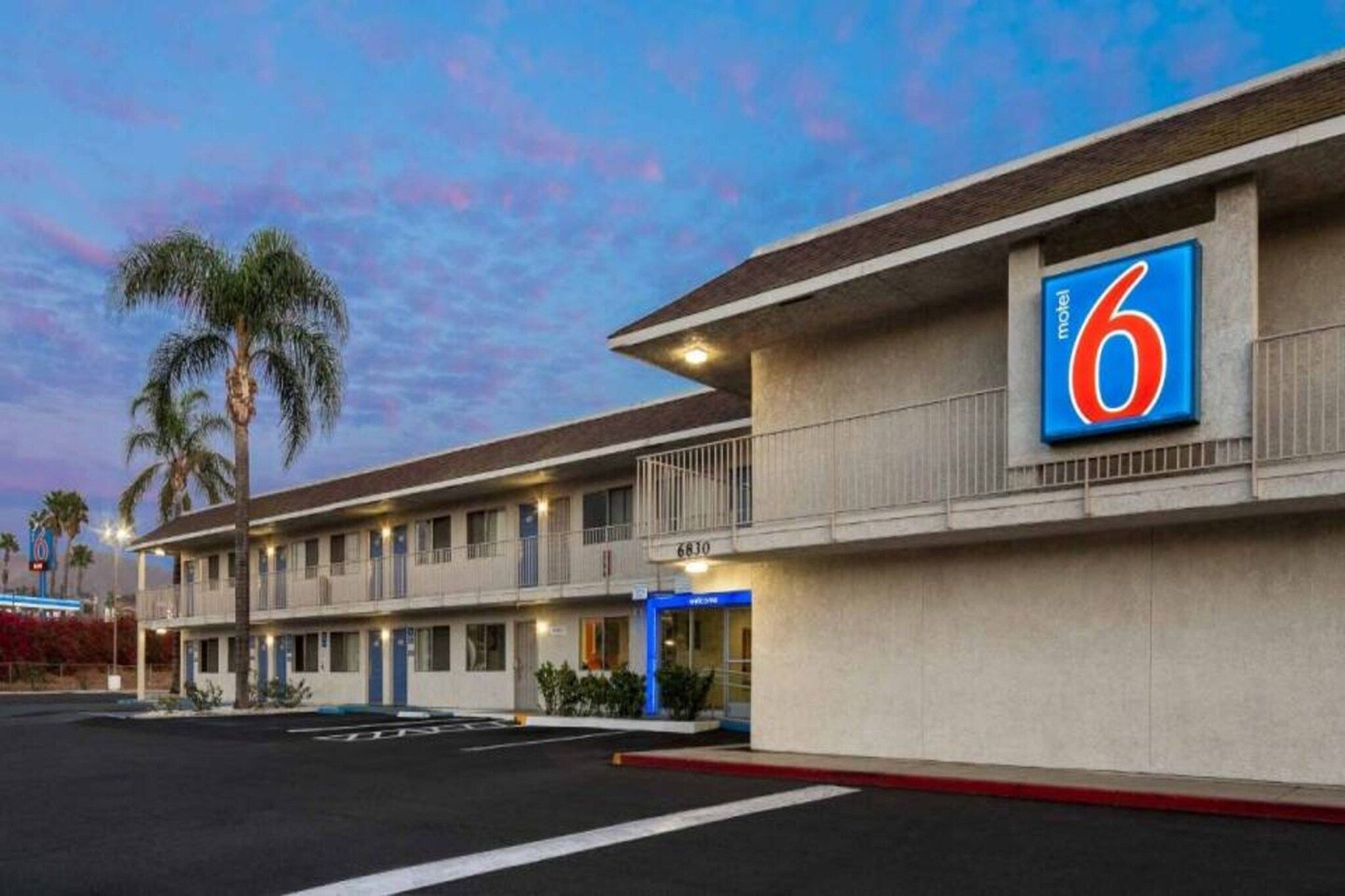 A motel with a large '6' sign, multiple rooms, and a parking lot.