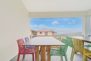 Un balcón con una mesa y sillas, con vistas a una zona residencial con casas y cielo despejado.
