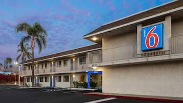 A motel with a large '6' sign, multiple rooms, and a parking lot.
