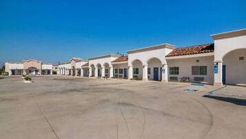 A row of white buildings with arched doorways and a clear blue sky.