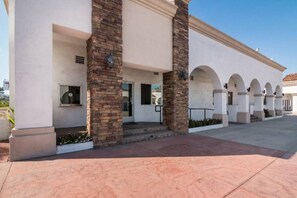 A building with a covered entrance, stone pillars, and a series of arches along the side.