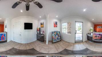A panoramic view of a hotel lobby with a reception desk, a television, and a magazine rack.