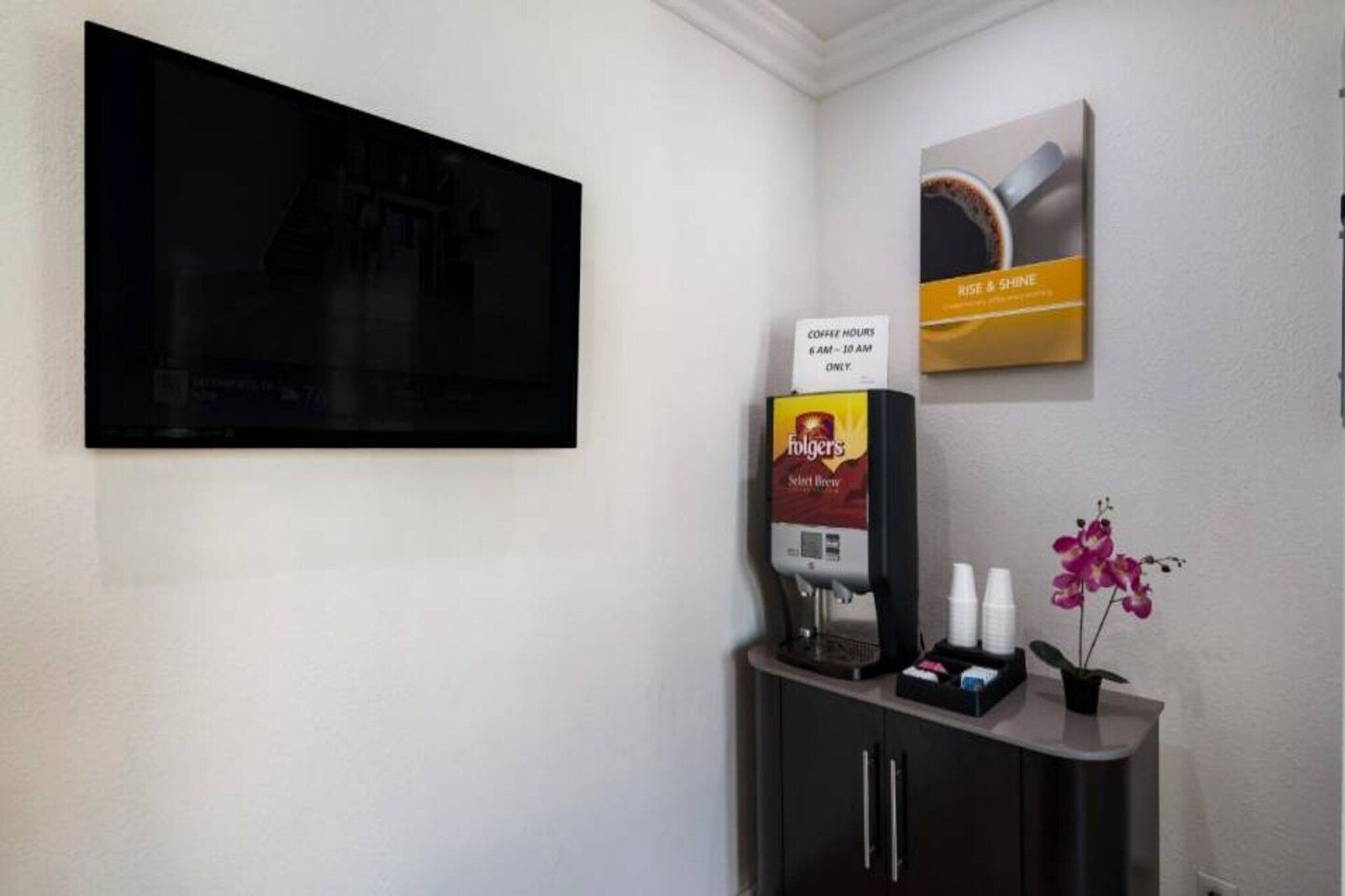 A coffee station with Folgers coffee, a coffee machine, and a sign indicating coffee hours.