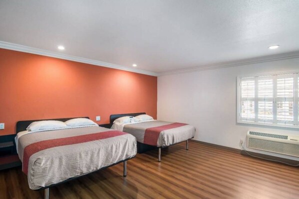 Una habitación con dos camas, una ventana con persianas, un radiador y suelo de madera.