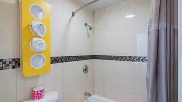 A bathroom with a shower, toilet, and a towel rack with three towels.