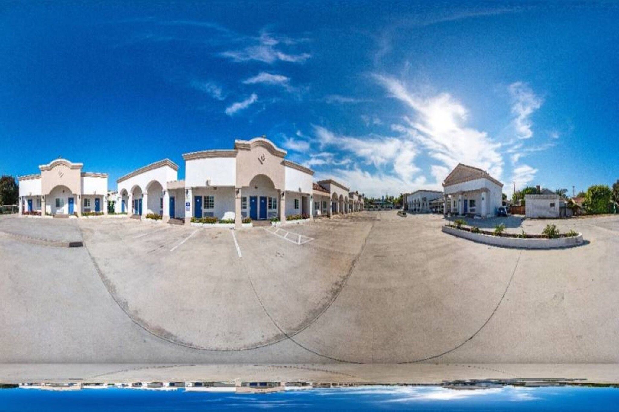 Un grand parking bordé d’une rangée de bâtiments, probablement un hôtel ou un complexe touristique, avec un ciel dégagé au-dessus.