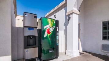 A 7UP vending machine and a water dispenser outside a building.
