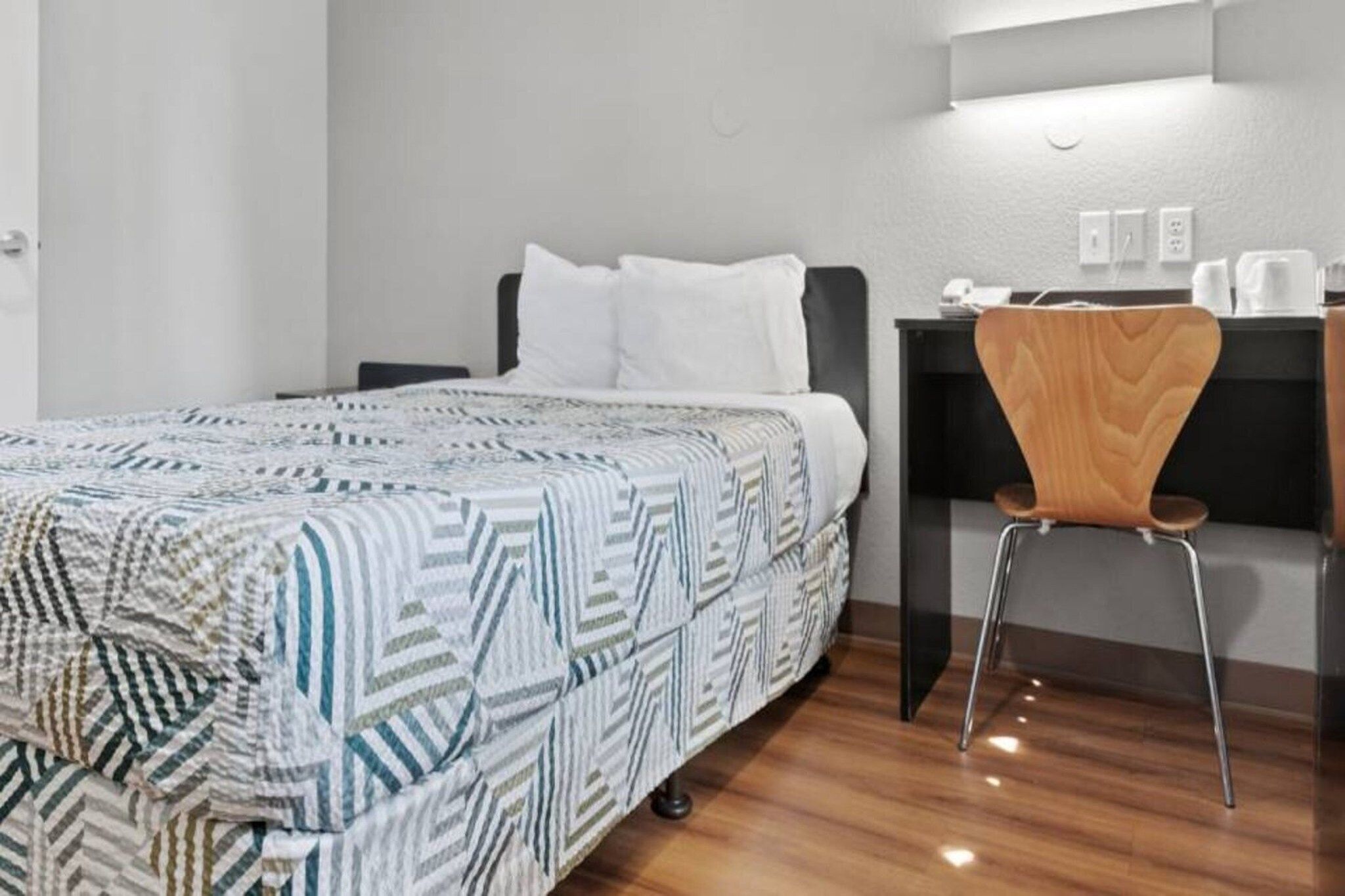 Ein Hotelzimmer mit Bett, Schreibtisch, Stuhl und einem kleinen Tisch.