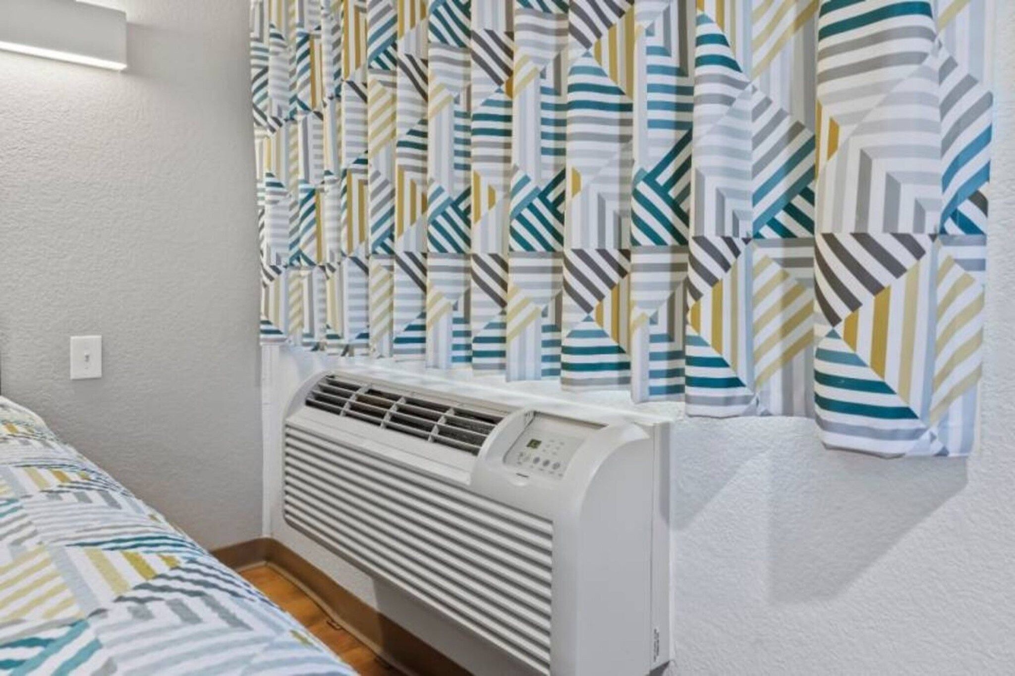 Una habitación con una cama, un radiador blanco y cortinas a rayas.
