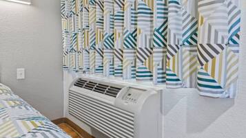 Una habitación con una cama, un radiador blanco y cortinas a rayas.