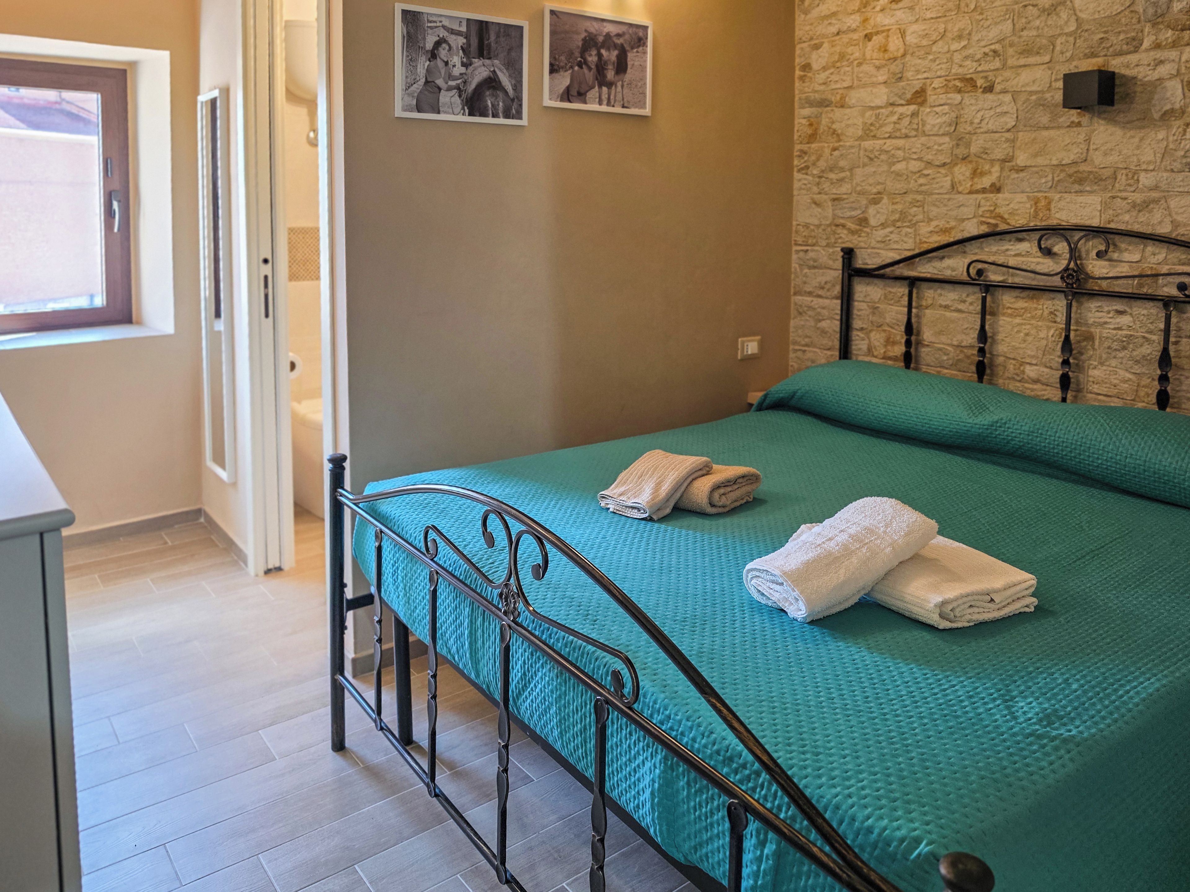A room with a bed, a stone wall, and a door.