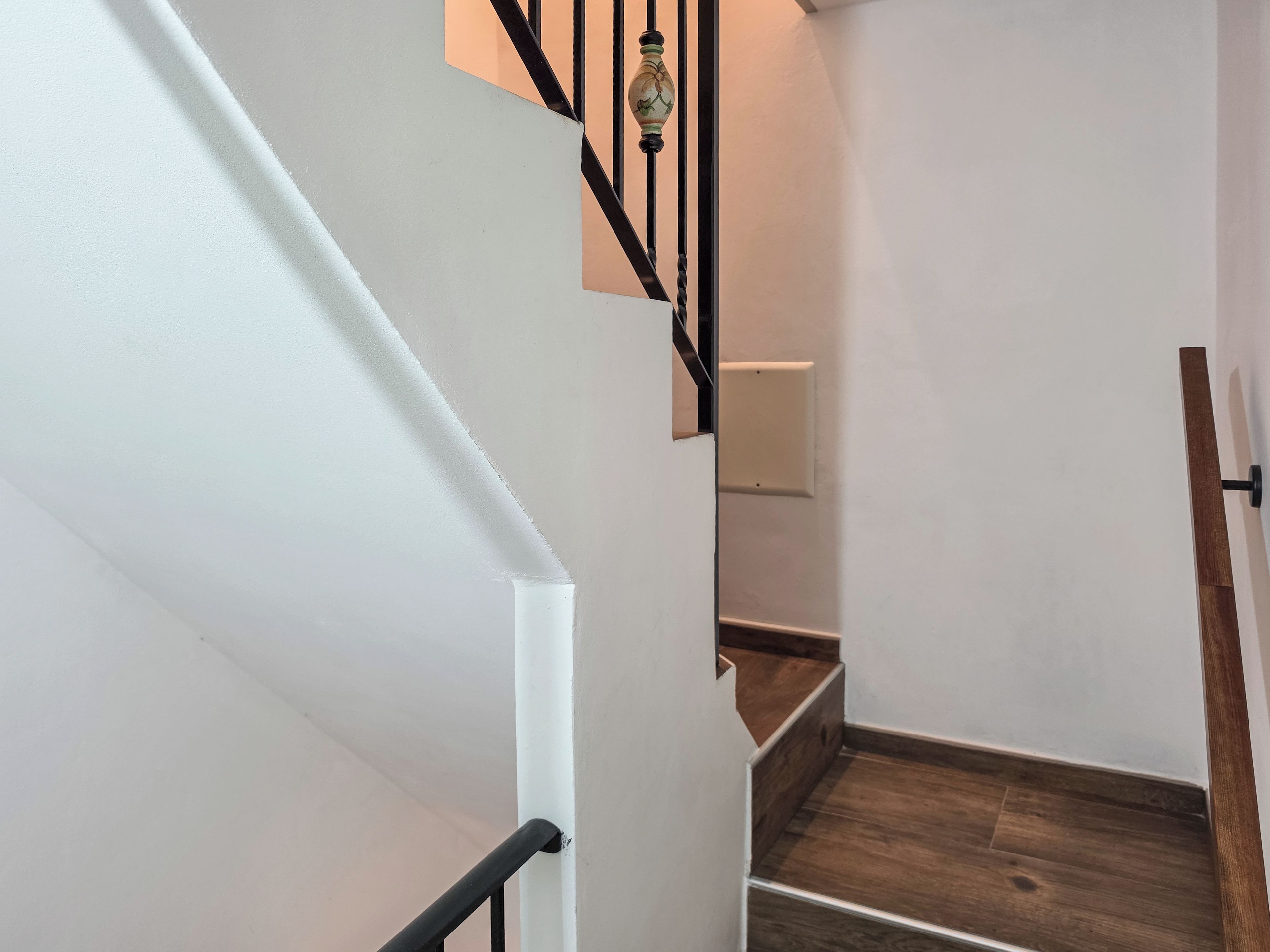 Una escalera con acabado de madera y barandal negro.