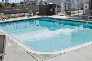 Ein rechteckiger Swimmingpool mit einer gefliesten Kante, umgeben von einer Betonplattform.