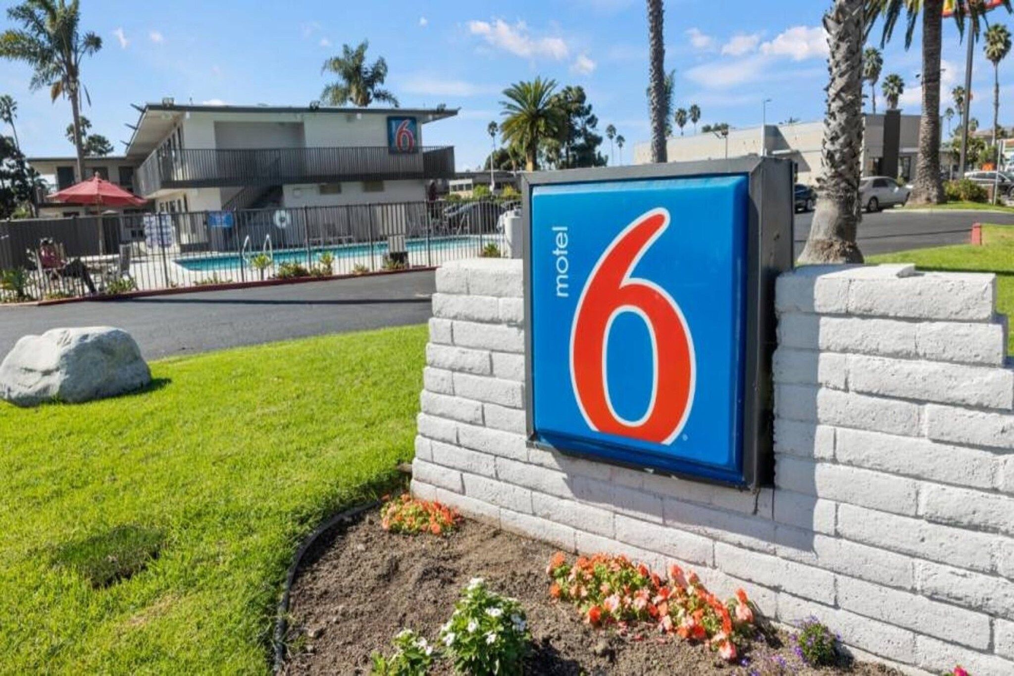 Un cartel de motel con el número 6, una piscina y un edificio al fondo.