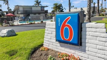 Un cartel de motel con el número 6, una piscina y un edificio al fondo.