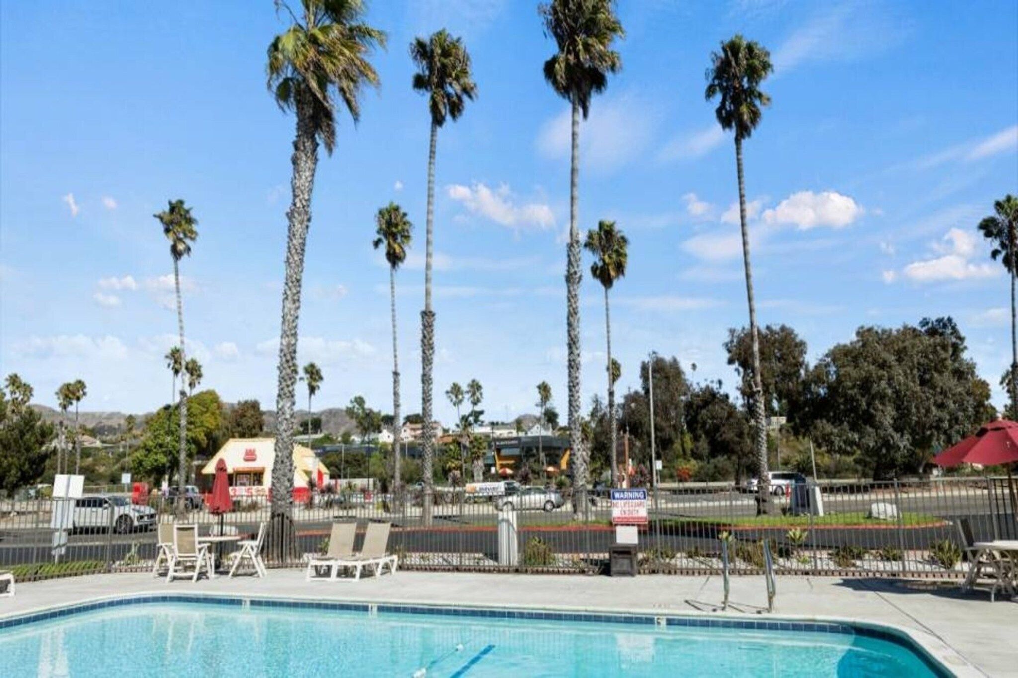 A swimming pool with lounge chairs and palm trees in the background.