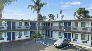 A motel with a parking lot, multiple rooms, and a car parked.