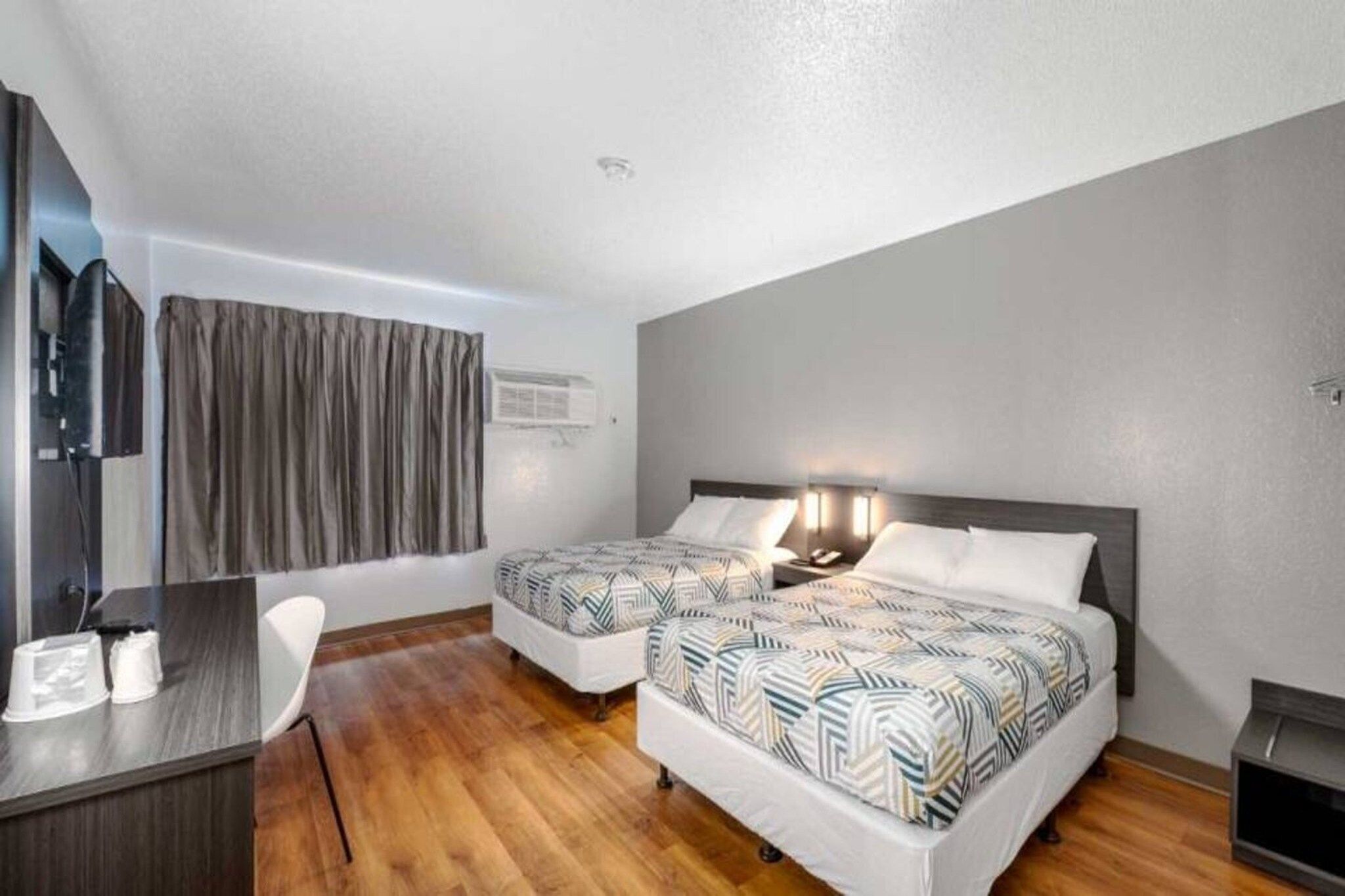 Een hotelkamer met twee bedden, een bureau en een stoel.