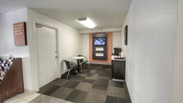 Un hall de hotel con una recepción, un televisor en la pared y una puerta que da a una habitación.